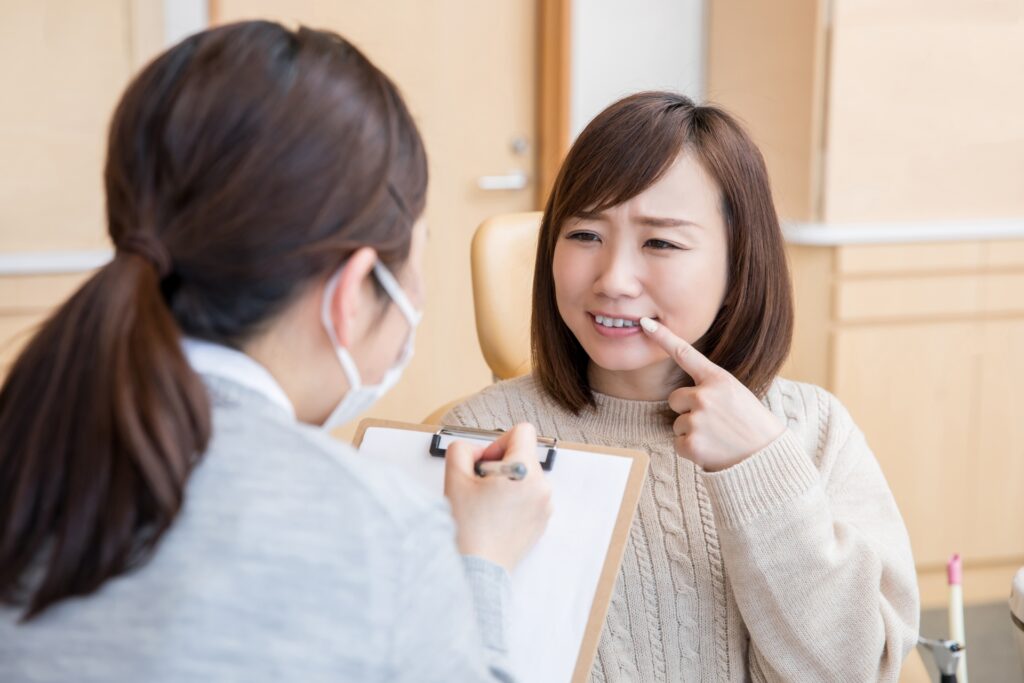 歯を歯科医に見せる女性